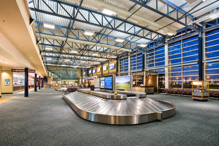 Baggage claim area at XNA airport in Fayetteville, AR, featuring exposed steel structure, large windows and baggage carousels