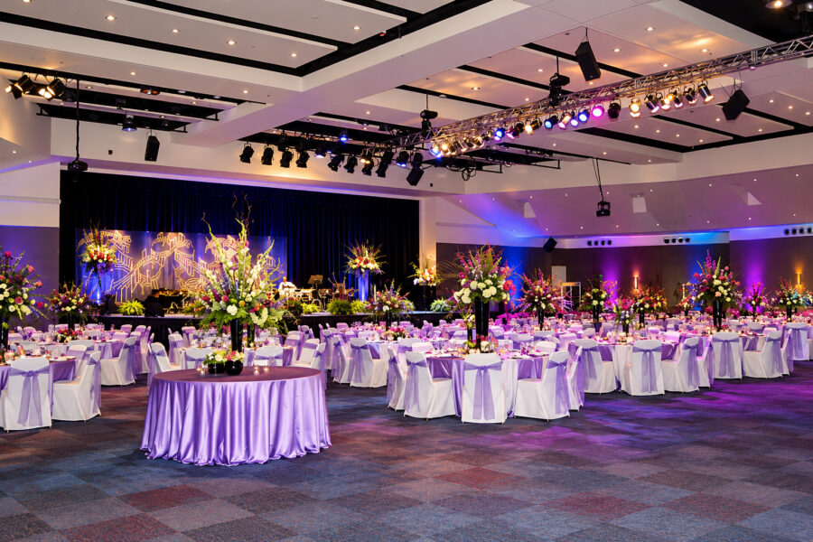 Hot Springs Convention Center ballroom in Arkansas featuring a large event space with a raised stage, integrated theatrical lighting and exposed ceiling beams.
