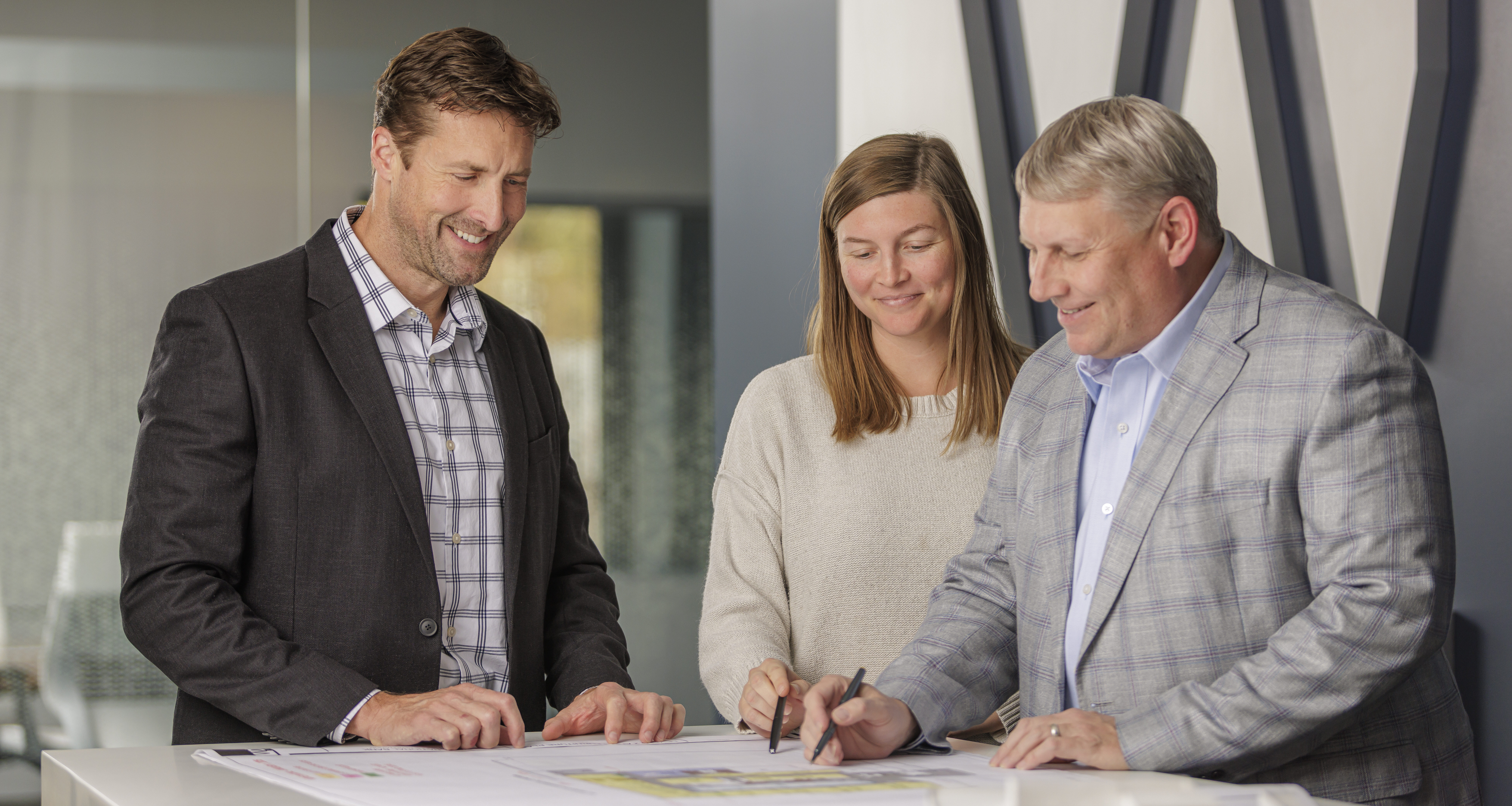 Three WDD Architects team members collaborating over architectural drawings during a design meeting.