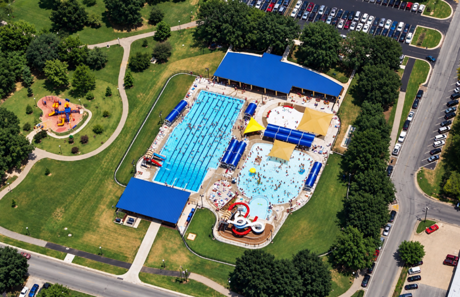 Aerial view of Springdale Aquatic Complex at Murphy Park designed by WDD Architects in Springdale, AR, showing the competition pool, recreational pools, water slides, bathhouse and surrounding park grounds.